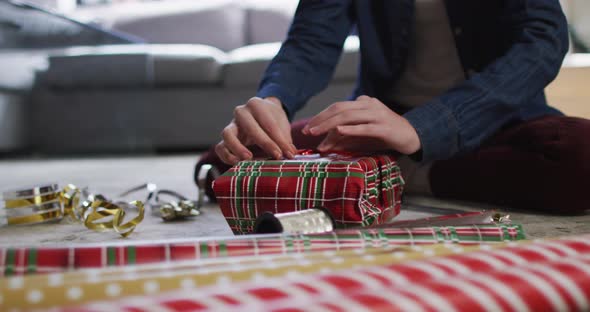 Mid section of woman wrapping Christmas presents at home