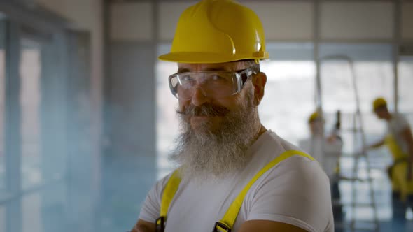 Portrait of Positive Elder Foreman in Safety Glasses and Hardhat Smiling at Camera