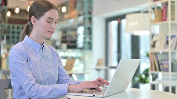 Laptop Use By Young Businesswoman Looking at Camera in Cafe