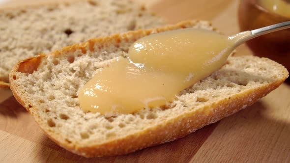 Spreading applesauce on a slice of brown whole grain bread close-up on wooden rustic table