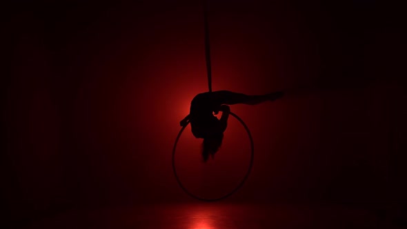 Aerial Acrobat in the Ring. A Young Girl Performs the Acrobatic Elements in the Air Ring on Red