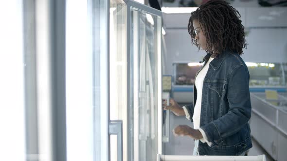 Focused Young Woman Choosing Goods From Fridge