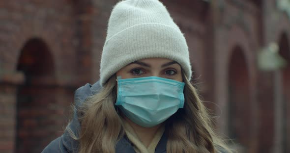 Close Up Portrait of a Beautiful Young Woman in a Hat Wearing Protective Medical Face Mask and