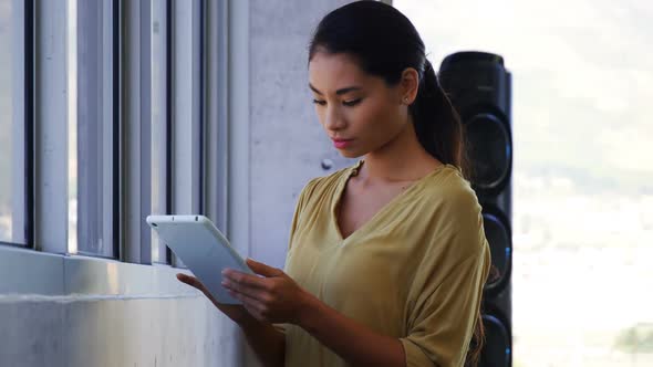 Executive standing near window and using digital tablet