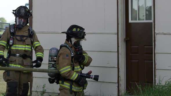 Firemen next to doorway with hose