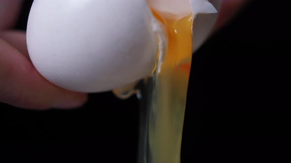 Closeup Cracking Egg in Female Caucasian Hands with White and Yolk Pouring Down in Slow Motion