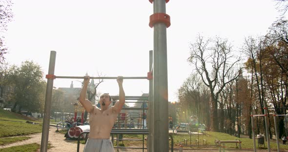 Young Man Is Doing Pull Ups on the Bar in Good Weather 