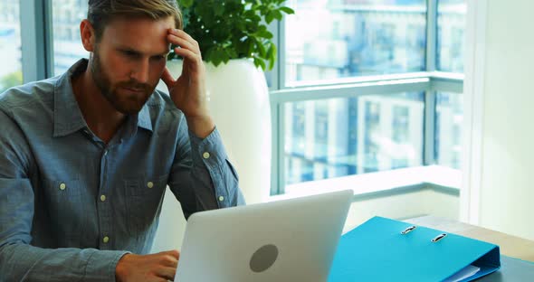 Male executive working over laptop in office