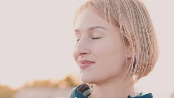 Portrait of Young Blond Woman Looking Into Camera Cute Smile Sun Shining Hair Fly Fluttering Wind