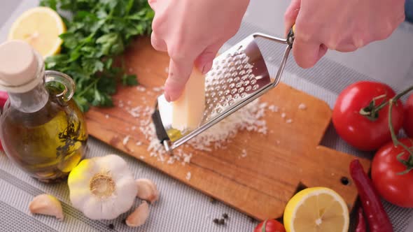 Woman Grates Parmesan Cheese for at Domestic Kitchen