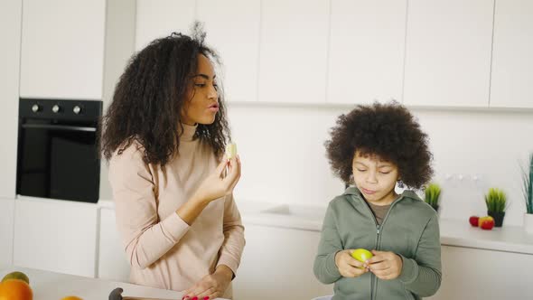 Mixed Race Mother and Son Eating Fruit in the Kitchen