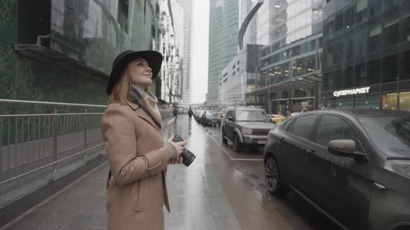 Female tourist holding camera outdoors in a modern city street