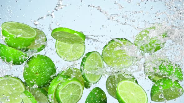 Super Slow Motion Shot of Flying Fresh Lime Slices and Water Side Splash at 1000Fps