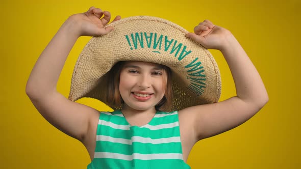 The Cute Little Girl is Hiding Under the Straw Hat and Smiling Cheerfully