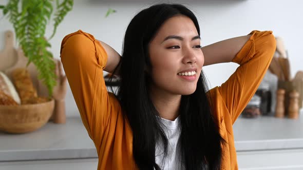 Happy Chinese Girl Freelancer Working From Home Sits in the Kitchen at the Workplace Takes a Break