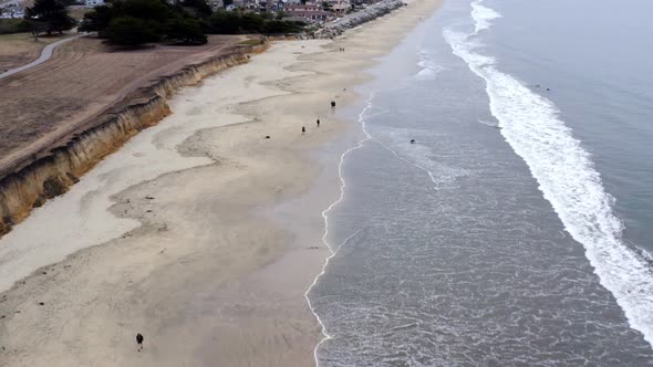 AERIAL: drone, half moon bay beach cliffs, people and shore,  flying forward view
