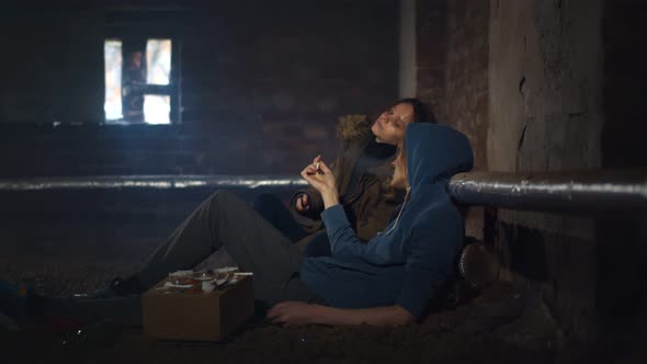 Drug Addicted Man and Woman Smoking Sitting on Floor in Dirty Basement