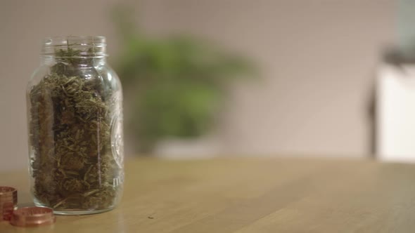 Pan to reveal marijuana in a jar, a grinder, and a vaporizer on a table