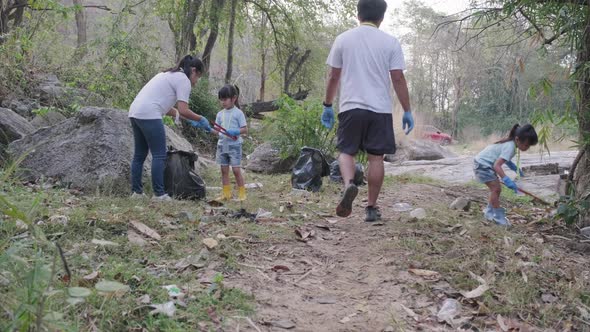 Group of Asian volunteer families collecting garbage and plastic by the river.