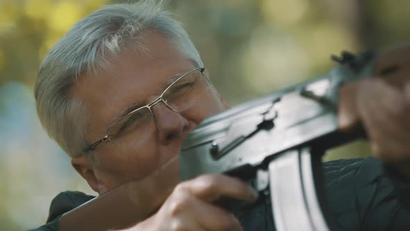 Elderly Gray Haired Man Holding a Gun in His Hands. Hunting Season