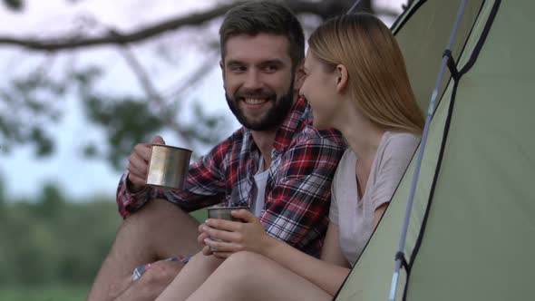 Smiling Couple Sitting in Tent, Drinking Hot Tea and Enjoying Cool View, Camping