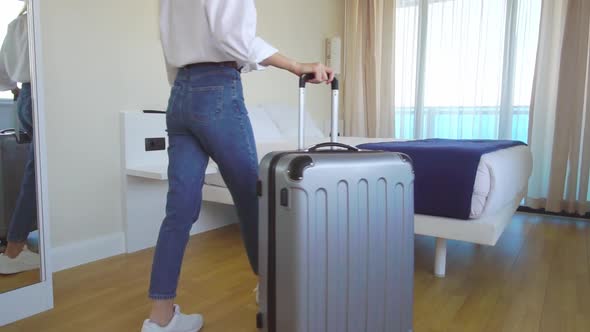 a woman enters the room with a suitcase and lies down on the bed.