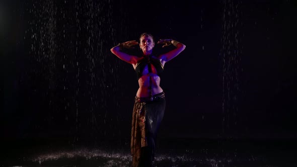Eastern Dance of Young Woman Standing Under Rain in Darkness Arabic or Indian Belly Dance