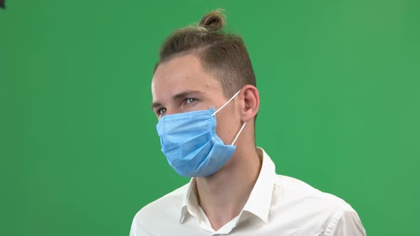 Young Man Takes Off Medical Mask on Green Screen Background
