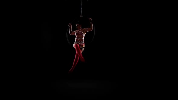 Woman Athlete Performs Acrobatic Stunts on the Air Hoop. Black Background. Slow Motion