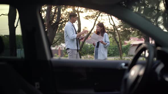 Young Caucasian Couple Talking Choosing Route for Road Trip Standing in Suburb Forest