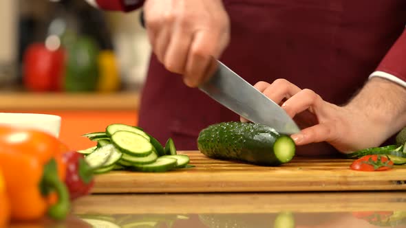 Chef chopping fresh, green  cucumber.