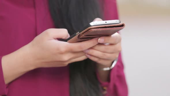 Woman with long hair and red dress texting on her phone close up