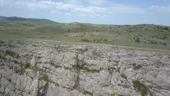 Two Girls Walking in Mountains on the Edge of an Impressive Cliff in Crimea