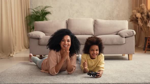 Little African American Girl Plays Game on Wireless Joystick and Rejoices Victory