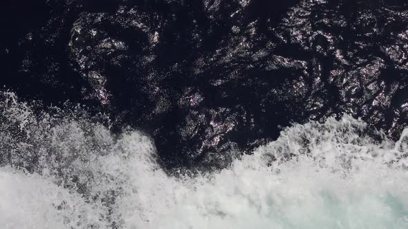 Powerful waves pulled out from fast moving boat, a huge stream of deep blue water with white foam ri