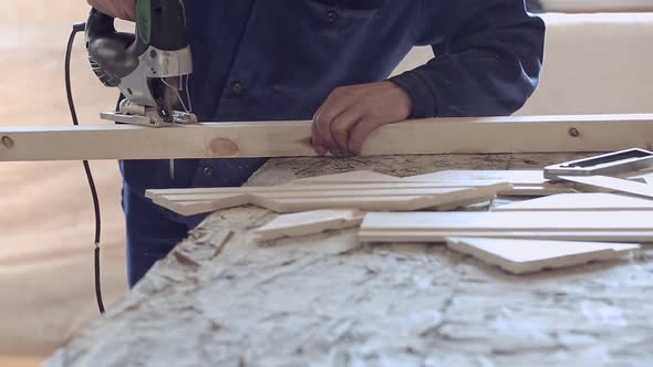 Man Sawing Wooden Plank with Jigsaw at Construction Site