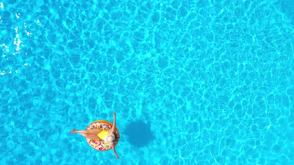 Aerial View of a Woman in Yellow Swimsuit Lying on a Donut in the Pool alt