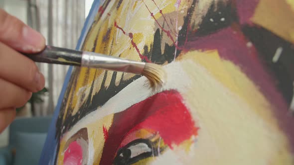 Close Up Of A Hand Holding Paintbrush Painting A Girl's Forehead On The Canvas