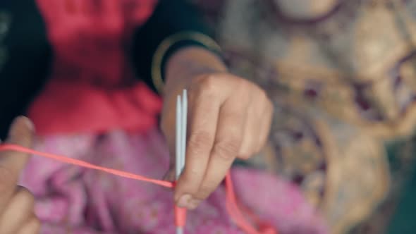 Woman starting a first row of knitting with red thread and needle crafts. 4k Close up footage of kni