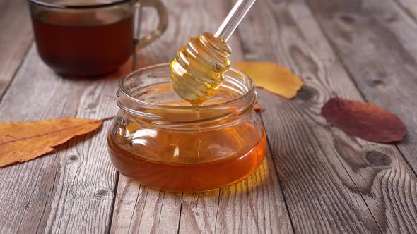 A Jar of Honey with Dipper on Rustic Table