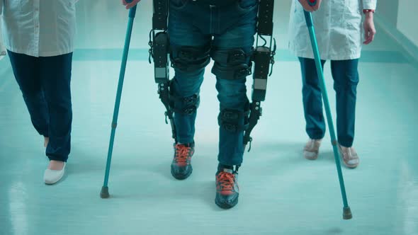 Nurses are Helping a Handicapped Man to Move in the Exosuit