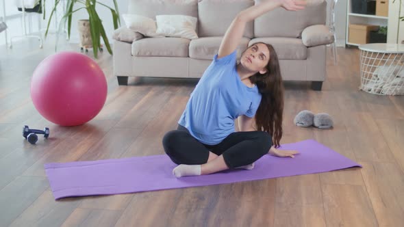 Young Pregnant Woman Doing Stretching and Fitness in the Living Room