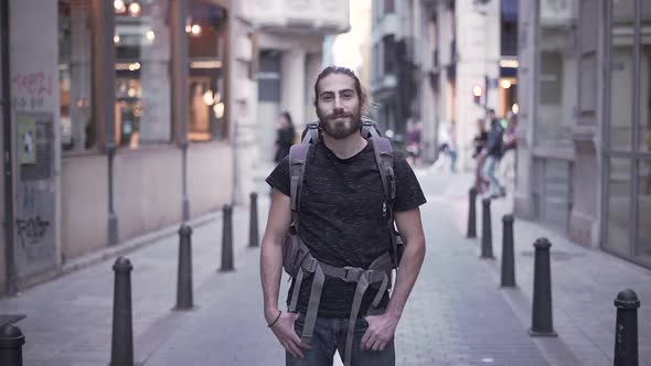 Attractive Backpacker Man Smiles for the Camera with Hands in Pockets in Valencia Spain