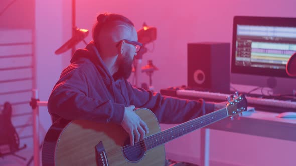 Concept of Hobby and Making Music. Young Bearded Man Plays the Guitar in a Home Music Studio