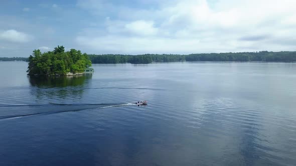 Drone aerial angle of boat going past small island on a lake