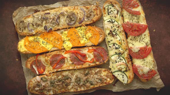 Assortment of Various Toppings Baked Sandwiches. With Melted Cheese, Vegetables, Tuna, Olives Spices