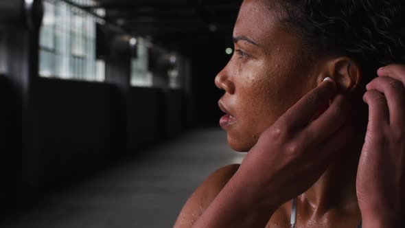 Portrait of african american woman standing in an empty building putting earphones in