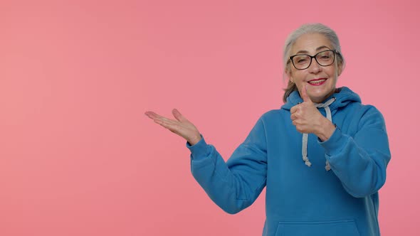 Senior Old Granny Woman Showing Thumbs Up and Pointing at Left on Blank Space Advertisement Logo