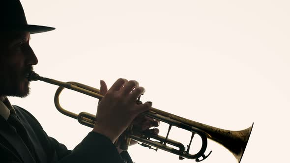 Man Licks Lips and Starts Playing Trumpet on White Background Side View