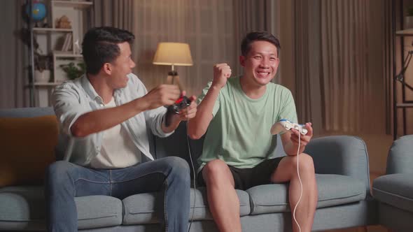 Asian Friends Playing Video Games And Celebrating Victory At Home